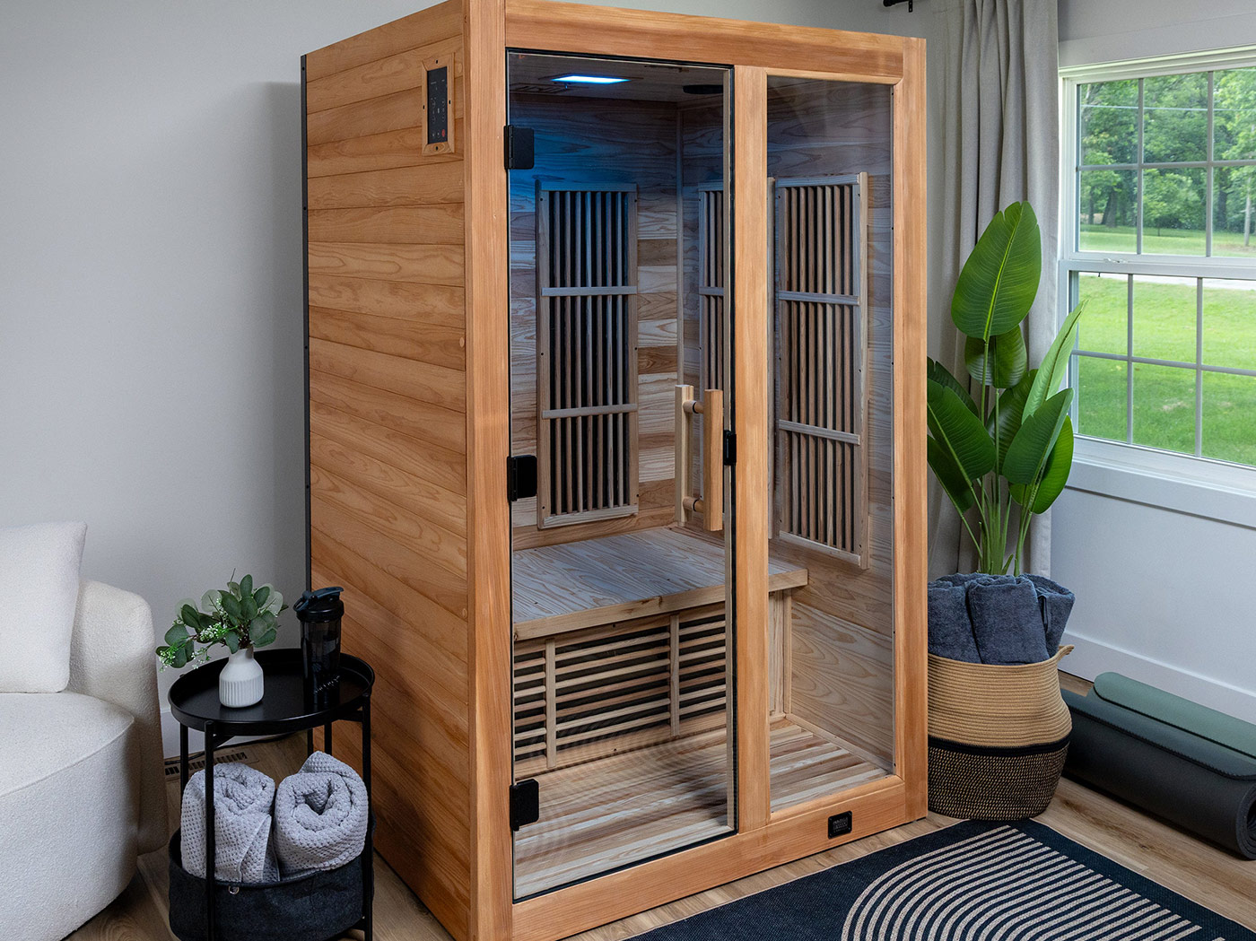 Modern two-person infrared sauna with glass door installed in home wellness room